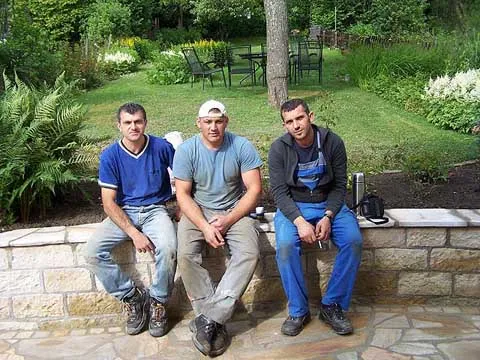 Das Krasniqi-Fachteam sitzt stolz auf einer fertiggestellten Natursteinmauer